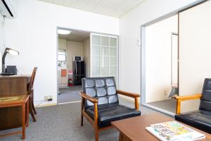 藤沢市にあるEnoshima Apartment Hotelの椅子2脚とテーブル付きの待合室
