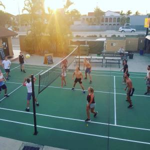 people playing a game of tennis on a tennis court at Maxmee Backpackers Resort in Gold Coast