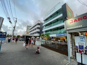 a group of people walking down a street with buildings at Israel Flat Tambaú in João Pessoa