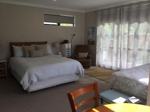 
a bedroom with a bed, desk, chair and a lamp at Abel Tasman Sands BnB in Marahau
