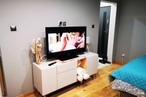 telewizor na białej komodzie w sypialni w obiekcie Apartament wysokim standardzie w mieście Kwidzyn