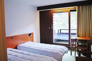 - une chambre avec un lit, une fenêtre et une table dans l'établissement Le Village Vacances de Luz Saint Sauveur, à Luz-Saint-Sauveur