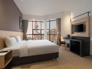 a hotel room with a bed and a desk and a television at Hotel 88 Blok M Jakarta By WH in Jakarta