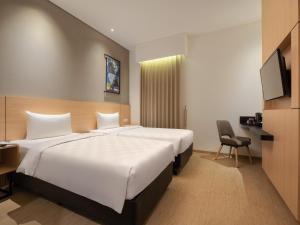 una camera d'albergo con due letti e una televisione di Hotel 88 Blok M Jakarta By WH a Giacarta