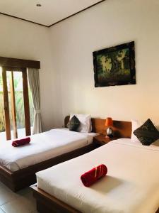 a hotel room with two beds and a window at Putu Homestay in Canggu