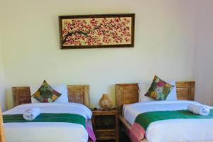 a bedroom with two beds and a picture on the wall at Putu Homestay in Canggu