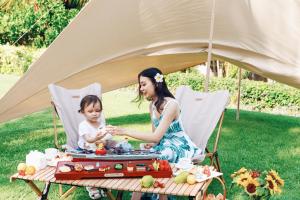 une femme et un enfant assis à une table de pique-nique dans l'établissement Horizon Resort & Spa Yalong Bay, à Sanya