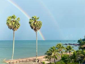 a rainbow over a beach with palm trees and the ocean at Saai Resort in Bang Saphan Noi