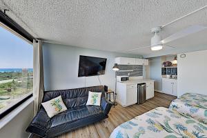 Hawaiian Monarch 2108 condo في هونولولو: غرفة بها أريكة وسرير ومطبخ