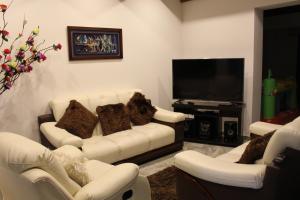 a living room with white couches and a flat screen tv at Casa Bella in Villa de Leyva