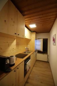 cocina con armarios de madera, fregadero y microondas en Bio Bauernhof - Mini Shetland Ponyhof "Almbauer" en Waidhofen an der Ybbs