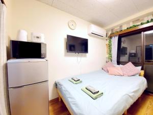 a small room with a bed and a refrigerator at nestay suite tokyo tabata in Tokyo