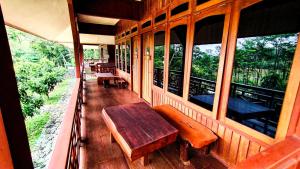 eine Veranda eines Hauses mit einer Holzbank und Fenstern in der Unterkunft Kasuari Exotic Resort Magelang in Magelang