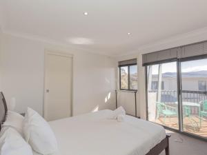 a white bedroom with a bed and a balcony at Northstar 10 17 Kirwan Close in Jindabyne