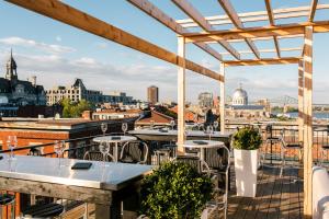 a view of the city from a rooftop bar with tables and chairs at Auberge du Vieux Port by Gray Collection in Montreal