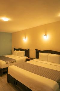 um quarto de hotel com duas camas e duas lâmpadas em VO´E em San Cristóbal de Las Casas