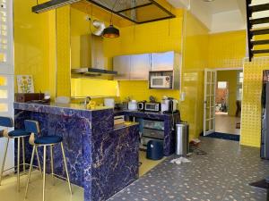 清邁的住宿－Gumpuju คำปู้จู้，厨房设有黄色的墙壁和带凳子的柜台。