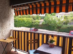 a balcony with a table and a car on a street at Studio Mag'Aline in Saint-Cyr-sur-Mer