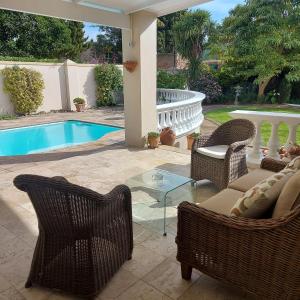 a patio with wicker furniture and a swimming pool at Rustic Manor Guest House in Tokai