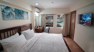 a bedroom with a bed with white pillows and a window at 1775 Adriatico Suites in Manila +37 photos
