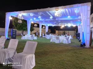 a marquee with white tables and chairs at night at Hotel Riddhi Inn in Udaipur