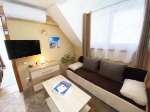 een woonkamer met een bank en een tv bij Apartman Siesta Bük in Bük