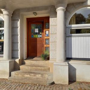 a house with a wooden door and stairs in front at Torget Vandrarhem in Kävlinge