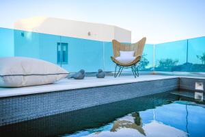 a chair sits next to a swimming pool in a house at Blue White Residence in Monolithos