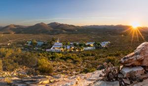 a house in the desert with the sun in the background at Sanbona Wildlife Reserve in Barrydale