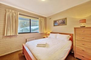 a bedroom with a large white bed with a window at Snow Ski Apartments 16 in Falls Creek