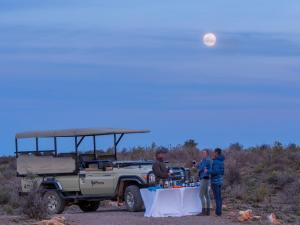 a group of people standing around a table in front of a vehicle at Sanbona Wildlife Reserve in Barrydale