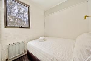 a small bedroom with a bed and a window at Snow Ski Apartments 18 in Falls Creek