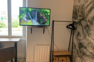a flat screen tv on a stand in a room at Le Travel, Studio cosy aux pieds de la Gare in Rennes