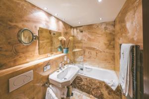 ein Badezimmer mit einem Waschbecken und einer Badewanne in der Unterkunft Antares Hotel in Zermatt