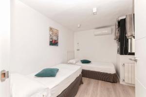 two beds in a room with white walls and wooden floors at AticoColón21 in Alicante