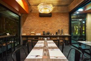 uma sala de jantar com mesas e cadeiras e uma parede de tijolos em Sand Dollar Boutique Hotel em Bang Sare