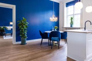 Augustenborg的住宿－'Gem Suites Luxury Holiday Apartments，一间拥有蓝色墙壁和桌椅的用餐室