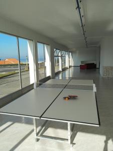 una mesa de ping pong en una habitación con ventanas en Area Surf House en Muros