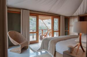 a bedroom with a bed and a chair and a window at Sanbona Wildlife Reserve in Barrydale