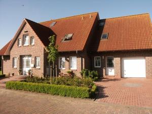 a brown brick house with a white garage at Ferienwohnungen Peters in Neuharlingersiel