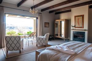 a bedroom with a bed and chairs and a fireplace at Sanbona Wildlife Reserve in Barrydale