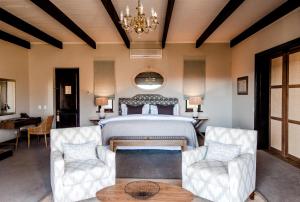 a bedroom with a large bed and two chairs at Sanbona Wildlife Reserve in Barrydale