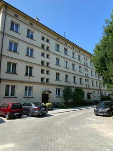 a large white building with cars parked in a parking lot at Apartament Jan III Sobieski in Rzeszów