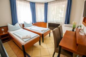 Zimmer mit 2 Betten, einem Schreibtisch und einem Tisch in der Unterkunft Richter Pansion in Budapest