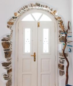 um arco com uma porta branca e uma parede de pedra em Blue & White: An Absolute Aegean dream house em Galini