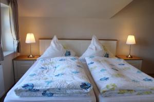 1 dormitorio con 2 camas con almohadas y 2 lámparas en Ferienwohnungen Peters en Neuharlingersiel