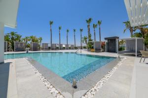 a swimming pool at a resort with palm trees at Tasia Maris Sands (Adults Only) in Ayia Napa