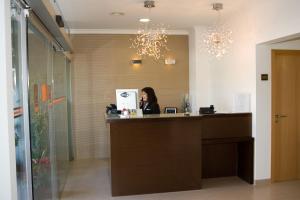 a woman sitting at a reception desk in a room at Hotel Paiva in Monte Gordo