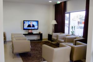 a waiting room with chairs and a flat screen tv at Hotel Paiva in Monte Gordo