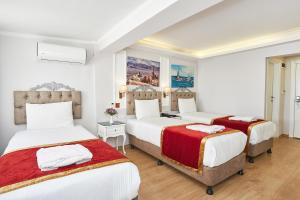 2 camas en un dormitorio con paredes blancas y suelo de madera en Beyazit Palace Hotel Cafe & Restaurant, en Estambul